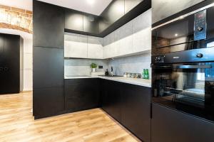 een keuken met zwart-witapparatuur en houten vloeren bij Apartament Królowa Luiza in Zabrze