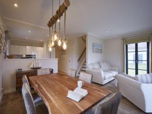 a kitchen and living room with a wooden table and chairs at Reetland am Meer - Premium Reetdachvilla mit 3 Schlafzimmern, Sauna und Kamin F04 in Dranske
