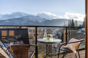 a balcony with a table and chairs and mountains at Apartament Szymoszkowa in Zakopane