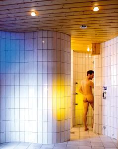 a naked man standing in a bathroom stall at Hotel Austria in Niederau