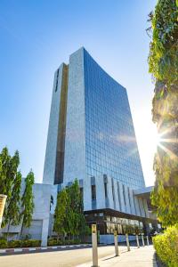 un edificio de cristal alto con el sol en el cielo en Hotel 2 Fevrier, Lomé en Lomé