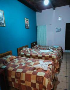 three beds in a room with blue walls at Hotel Lirice Colonial in Comitán