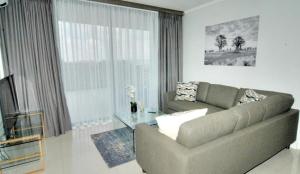 a living room with a couch and a glass table at Stylish Modern 2BR in Waterfall Ellipse - Sleeps 4 - Fast WiFi - Secure Parking in Midrand