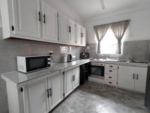 a kitchen with white cabinets and a microwave at 7-on-Burger in Polokwane
