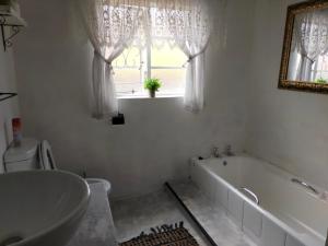 een badkamer met een bad, een wastafel en een raam bij 7-on-Burger in Polokwane
