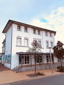 un bâtiment blanc au bord d'une rue dans l'établissement Ferienwohnung Strandeck - Inklusive Strandkorb in den Sommermonaten, à Göhren