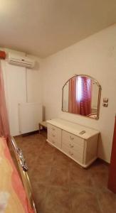 ein Schlafzimmer mit einem Spiegel, einer Kommode und einem Bett in der Unterkunft Melana Apartment in Tiros