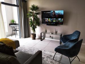 a living room with a couch and chairs and a flat screen tv at Trilogy Apartment - Sapphire Gold in Pretoria