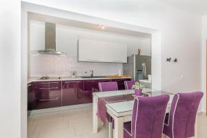 a kitchen with purple chairs and a dining table at Apartment Mario in Strožanac