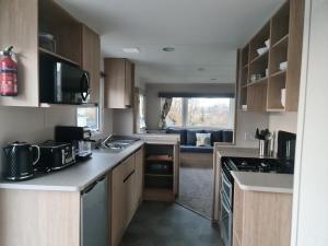 a kitchen with wooden cabinets and a living room at Escape City Caravan in Lytchett Minster