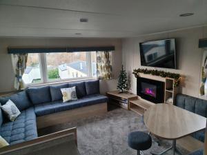 a living room with a blue couch and a tv at Escape City Caravan in Lytchett Minster