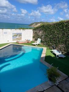 a blue swimming pool with a view of the ocean at Apartamentos Ponta do Sol in Natal