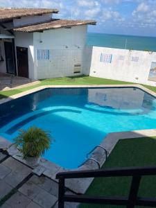 une grande piscine bleue en face d'une maison dans l'établissement Apartamentos Ponta do Sol, à Natal