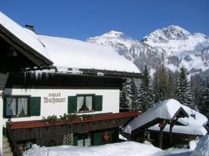 a snow covered building with mountains in the background at Almhaus Bachmann in Sonnenalpe Nassfeld