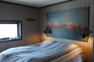 a bedroom with a bed with a painting on the wall at Skarvhytta - moderne hytte med flott beliggenhet in Hol