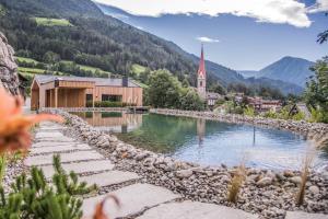 a small village with a church and a body of water at Chalet & Appartement Zingerlehof Trens in Campo di Trens