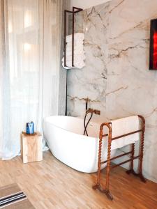 een badkamer met een bad en een marmeren muur bij B&B Tholen t’Uusje in Tholen