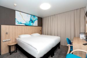 a bedroom with a large white bed and a desk at AMAKS Park Hotel in Voronezh