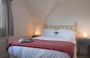 a bedroom with a bed with a red blanket on it at Old Forge Close, Pretty 3 Bed Cottage in Bledington, The Cotswolds in Bledington