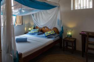 a bedroom with a canopy bed with blue pillows at Kiponda B&B in Zanzibar City
