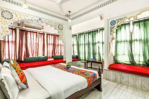 a bedroom with a large bed with red curtains at Hotel Pichola Haveli in Udaipur