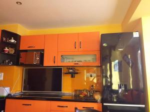 een keuken met oranje kasten en een zwarte koelkast bij Apartament Kostov Sliven in Sliven