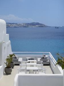 a row of white chairs and tables and the ocean at Nimbus Mykonos in Agios Stefanos