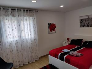 a bedroom with a red bed and a window at Dina House in Boticas