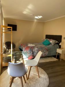 sypialnia z łóżkiem oraz szklanym stołem i krzesłami w obiekcie Studio Victoria 400 w mieście Concepción