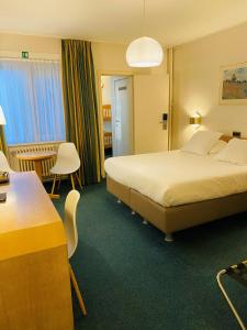 ein Hotelzimmer mit einem Bett, einem Tisch und Stühlen in der Unterkunft Hotel Prado in Ostende