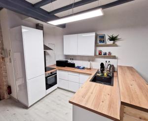 une cuisine avec des placards blancs et un comptoir en bois dans l'établissement Appartement Ma Douce Charente - Superbe T3 Design et Fonctionnel - Hyper Centre à Saintes, à Saintes