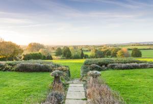 a garden with a stone path in the middle of a field at Charingworth Manor in Chipping Campden