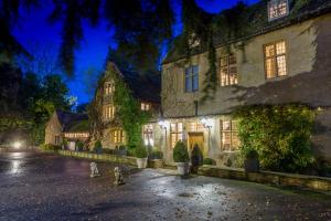an old house with lights on in a yard at night at Charingworth Manor in Chipping Campden