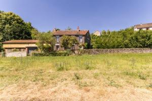 a house in a field next to a stone wall at Les Barboulottes in Châtillon-en-Bazois