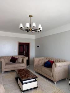 a living room with two couches and a chandelier at Apple Tree Apartment in Nairobi