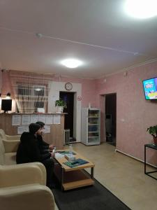 a man sitting on a couch in a living room at Гостиница Мещерский Дворик in Meshcherino