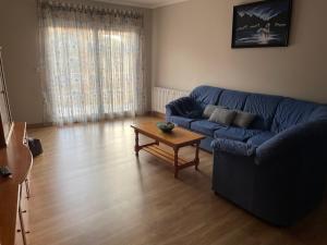 A casa Daló في Folgoso: غرفة معيشة مع أريكة زرقاء وطاولة