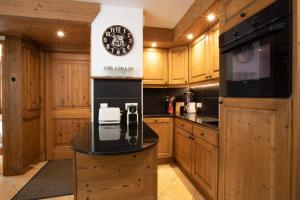 a kitchen with wooden cabinets and a clock on the wall at Villa Vallet- Newly renovated 2 bedroom nestled near the main street in Chamonix-Mont-Blanc