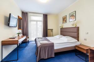 a hotel room with a bed and a desk and a television at Willa Carlton in Zakopane