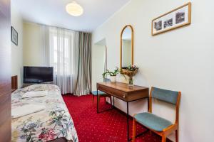 a hotel room with a bed and a desk and a mirror at Willa Carlton in Zakopane