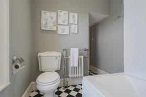 a bathroom with a white toilet and a checkered floor at Big Pink House in Mealsgate