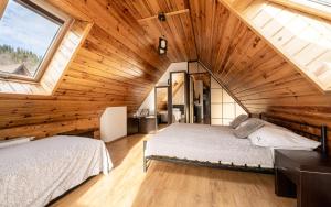 a attic bedroom with two beds and a large window at WILLA GALANTÓWKA in Zakopane