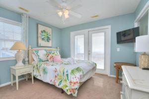 a bedroom with blue walls and a bed with a tropical bedspread at Just Peachy in Oak Island +39 photos