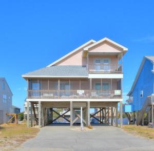 a large house with a large deck on a beach at Just Peachy in Oak Island