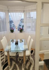 une salle à manger avec une table en verre et des chaises blanches dans l'établissement Apartman Hana, à Sanski most