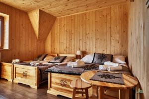 two beds in a wooden room with a table at Pod Strumykiem in Czarny Dunajec