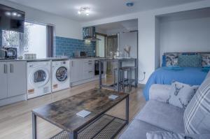ein Wohnzimmer mit einem Sofa, einem Tisch und einer Küche in der Unterkunft Haylands Hideaway - 1 Bedroom Apartment - Jameston in Manorbier
