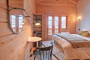 a bedroom with a bed and a table and a mirror at Chalet Jonquilles - Au pied des pistes de La Tania in Courchevel