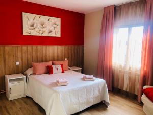 um quarto com uma cama e uma parede vermelha em Casa El Tejar em Las Navas del Marqués