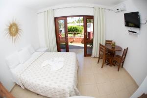 a bedroom with a bed and a table and a television at Pousada Recanto dos Milagres in São Miguel dos Milagres